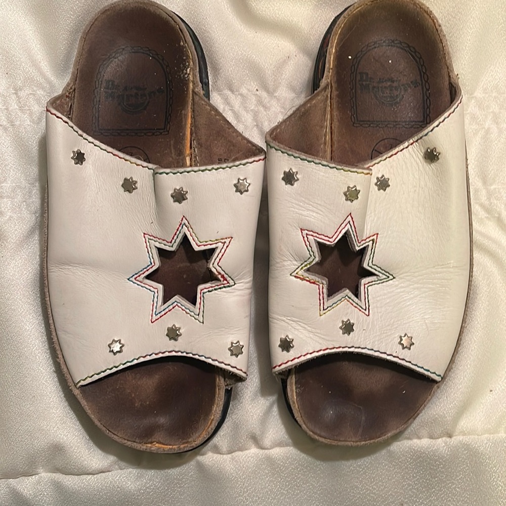 Dr. Martens white leather slip ons with multicolored stitching and silver studs.